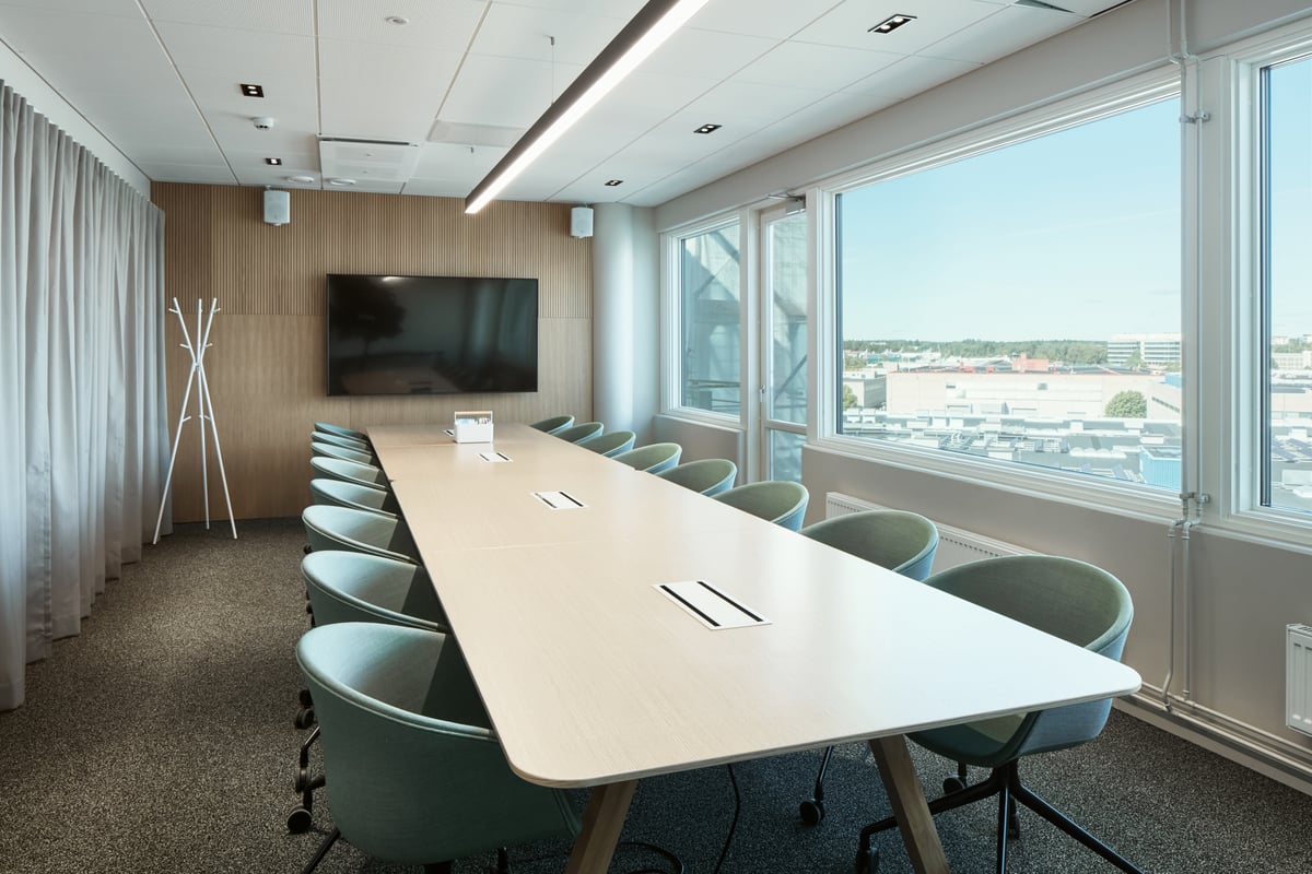 Valimo Parkin Koivu-kokoustila, jossa pitkän pöydän äärellä tuoleja, sekä pöydän päässä näyttö ja ikkunasta 7. kerroksen näkymät.