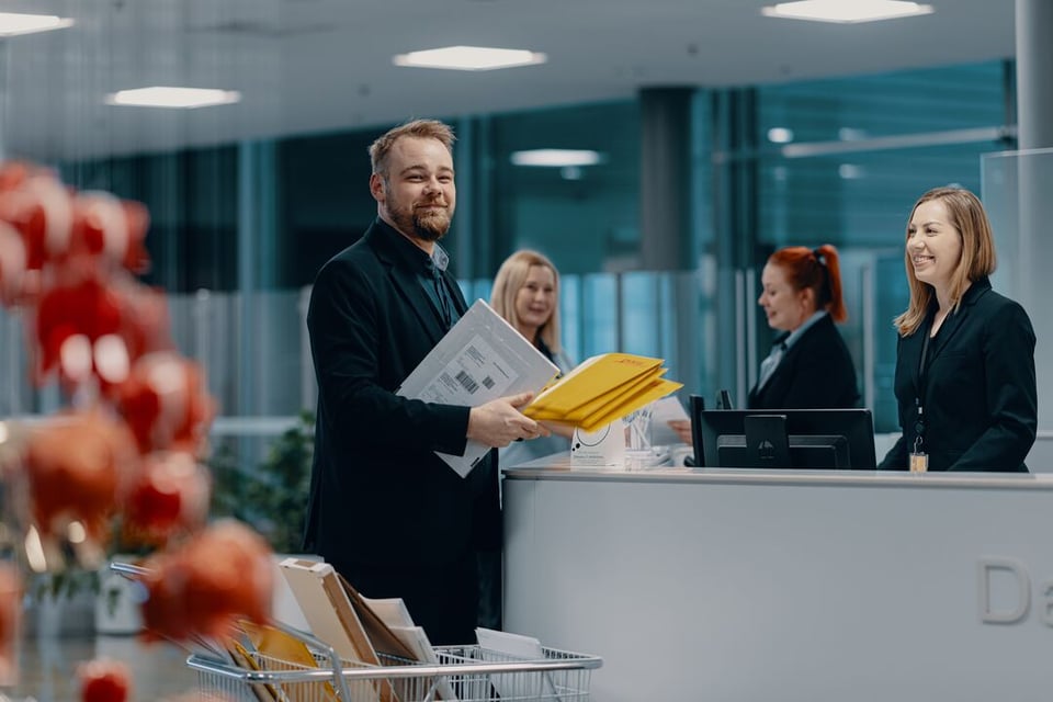 ISS:n aulapalvelutyöntekijöitä Danske Bankin aulassa. Vastaanottovirkailija hymyilee aulan vastaanottotiskin takana, kun toinen työntekijä on tuomassa saapunutta postia.