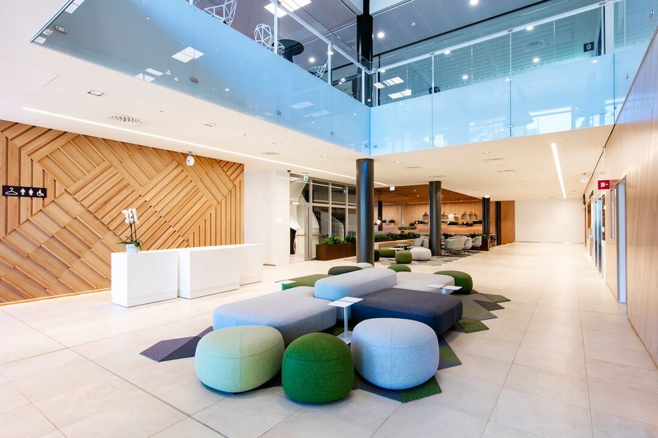 Ultimes Business Gardenin aulan sohvaryhmä, joka koostuu harmaista ja vihreistä sohvan osista, taustalla kiinteisön ravintolasali.