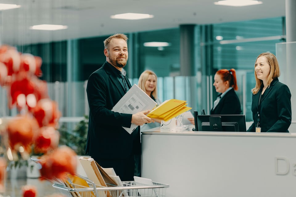 ISS:n aulapalvelutyöntekijöitä Danske Bankin aulassa. Vastaanottovirkailija hymyilee aulan vastaanottotiskin takana, kun toinen työntekijä on tuomassa saapunutta postia.